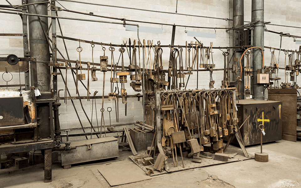 An assortment of blacksmithing tools including tongs and swages. 